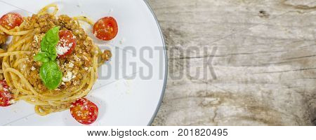 Italian spaghetti bolognese with tomato and basil on wood background