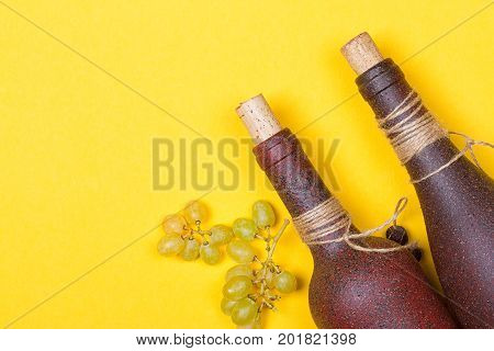 bottle of white wine with grapes on a yellowbackground