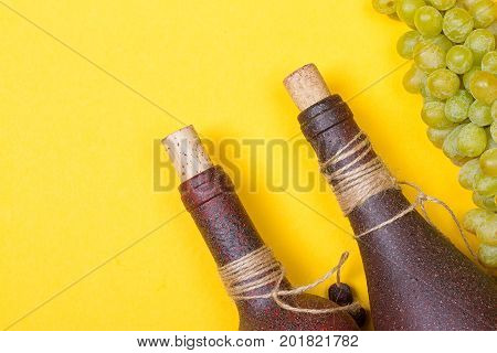 bottle of white wine with grapes on a yellowbackground