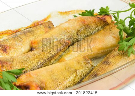 Baked notothenia fish in the glass casserole dish closeup