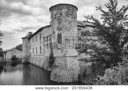 Lisignano (Piacenza Emilia Romagna Italy): the historic castle near Agazzano with waterlilies in the moat water. Black and white