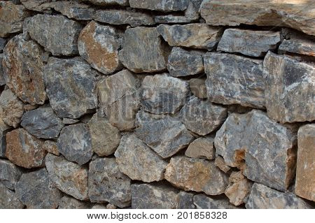 Ancient stone wall of the fortress. Masonry of old stones and bricks. Beautiful unusual background.