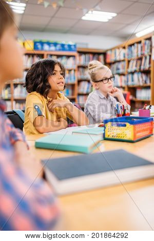 adorable little kids sitting at desk in library