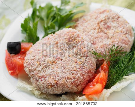 Raw Semifinished Cutlet With Greens On A Plate. Isolated