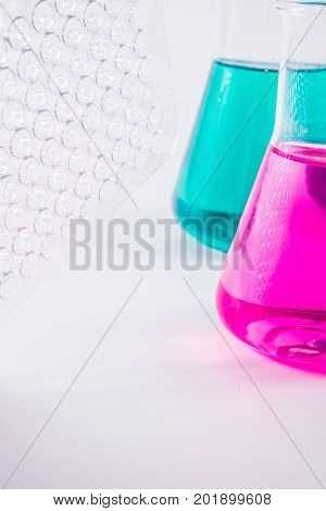 research, science and clinic background. 96 well micro plate and  laboratory beakers with colorful liquids and reagents.
