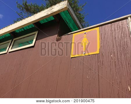 A Female Sign Outside an Outdoor Toliet