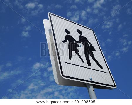 A crosswalk sign against a blue cloudy sky
