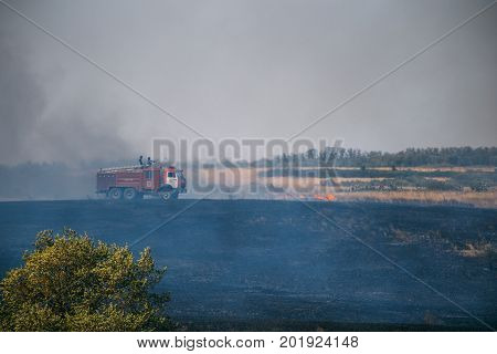 Rostov Region, Russia 20 AUGUST 2017: A car of firefighters or rescuers of the Emergencies Ministry extinguishes wildfires on the fields in the Rostov Region. Summer fires in the fields and forests