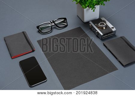 A set of black office accessories, glasses, green flower and smart on gray background. Flat lay. Still life. Mock-up