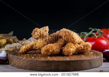 Chicken breast nuggets with vegetables on wooden background. Pile of crispy homemade baked chicken nuggets cooling. copy space.