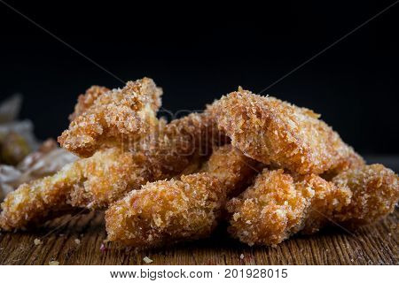 Chicken breast nuggets on wooden background. Pile of crispy homemade baked chicken nuggets cooling. copy space. Close up.