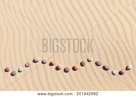 Pattern of colored pebbles on clean sand. The concept of peace and contemplation. Flat lay top view. Zen background harmony and meditation concept