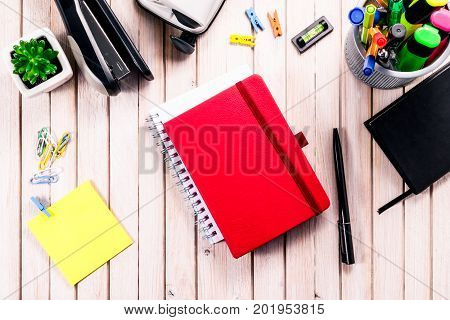 Top view workspace mockup on wooden background with blank notebook with copy space, pen, tacker, punch, clips and accessories. Overhead view. Flat lay, top view