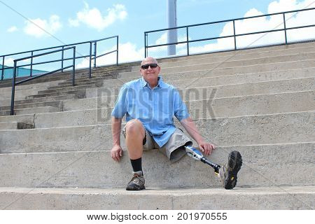 Man with prosthetic leg seated on concrete bleachers