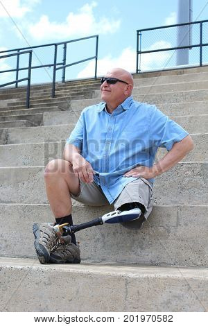 Amputee man seated with leg and prosthesis crossed, hand on hip