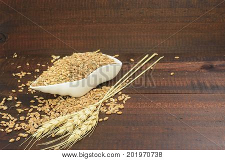 Wheat grains and spikes on brown wooden background