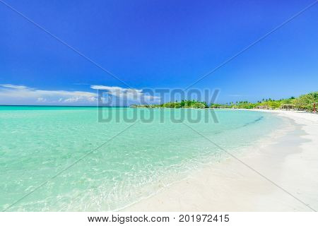 nice amazing inviting view of tropical white sand beach and tranquil turquoise ocean on blue sky with people in background at Cayo Coco Cuban island, sunny summer beautiful day