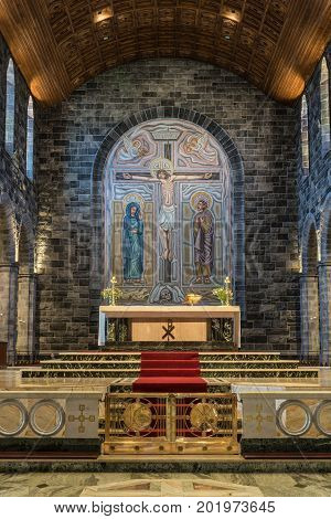 Galway Ireland - August 5 2017: Chancel sanctuary with altar on marble floor with Crucifixion backdrop seen from closeby. Colorful combination of floors walls ceilings walls and altar decorations.