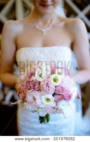 Beautiful bride is holding a wedding colorful bouquet. Beauty of colored flowers. Close-up bunch of florets. Bridal accessories. Female decoration for girl. Details for marriage and for married couple