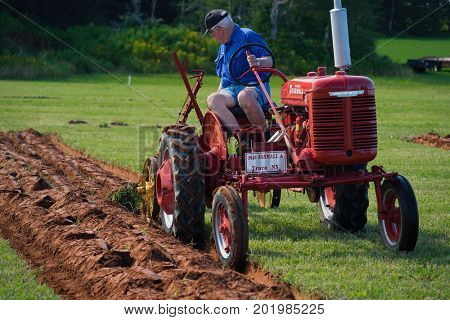 DUNDAS, PRINCE EDWARD ISLAND, CANADA - 25 Aug: Competitor plows with antique tractor at the PEI Plowing Match and Agricultural fair on August 25, 2017 in Dundas, Prince Edward Island.