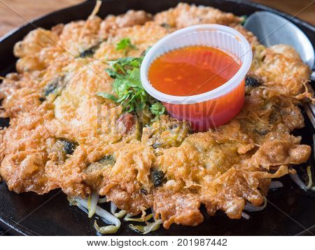 Hoy tod a classic Thai course consisting of an omelet with mussels or oysters on a bed of bean sprouts served on an iron hot plate with chili sauce. Shallow depth of field with the nearest part in focus.