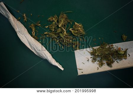 Joint of marijana and tobacco paper on the desk top overhead closeup photo
