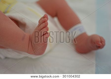 Close-up Newborn Baby At The Hospital With Identify Tag On Feet And Diaper.