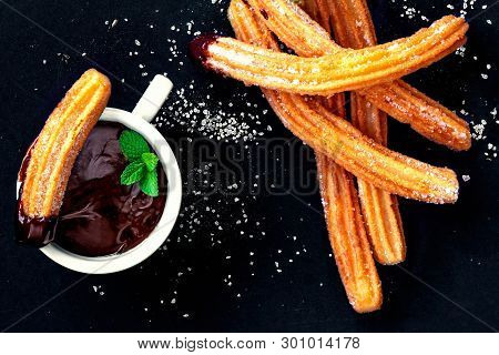 Churros With Sugar And Chocolate Sauce On A Black Background. Churro - Traditional Spanish Dessert. 