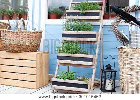 Wicker Baskets Next To The Garden Equipment Against The Wall Of A Blue Country House. Summer Seasona