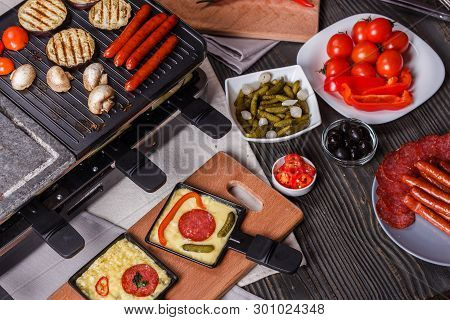 Young Woman Is Preparing A Traditional Swiss Cheese Raclette
