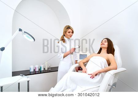 Pretty Blonde Beautician Doctor Doing Rf-lifting Procedure For Woman Laying In A Beauty Salon. Hardw