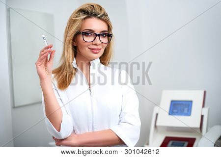Portrait Of Young Attractive Beautician Doctor With Syringe In Hand. Cosmetologist Holding Medical T