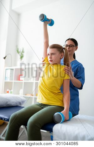 Tranquil Well-behaved Girl Carrying Heavy Sportive Equipment
