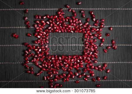 Garnet Seeds Make A Frame In Black Wood Background
