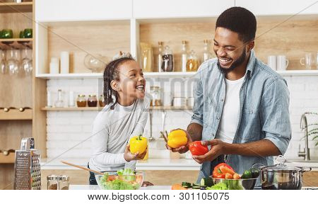 Afro Ameriacan Father And His Little Daughter Cooking Together, Having Fun. Happy Family Culinary Co