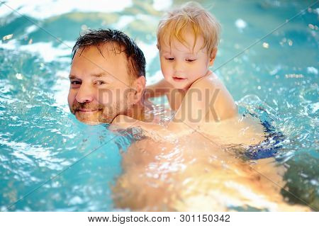 Happy Smiling Little Boy With His Father In Swimming Pool. Cute Child Swims And Having Fun. Kids Spo