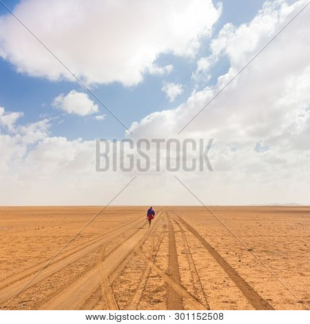 Solitary Masai Worrior Walking Along Salt Lake Desert Road In Kenya, Amboseli Natural Park, Africa