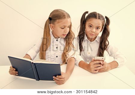 Innovation And Archaism Concept. Children Read Paper Book And Electronic Mobile Device Using Innovat