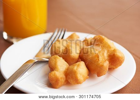 A Plate Of Delicious Deep Fried Dough Stick With Sweetened Condensed Milk On Top. A Glass Of Otange 
