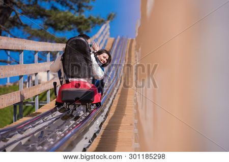 Excited young couple driving alpine coaster while enjoying beautiful sunny day in the nature