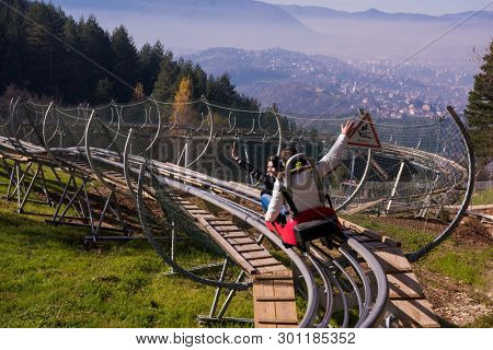 Excited young couple driving alpine coaster while enjoying beautiful sunny day in the nature
