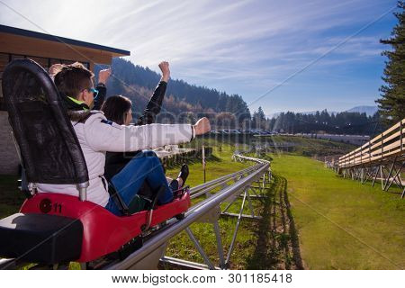 Excited young couple driving alpine coaster while enjoying beautiful sunny day in the nature
