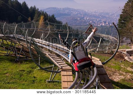 Excited young couple driving alpine coaster while enjoying beautiful sunny day in the nature