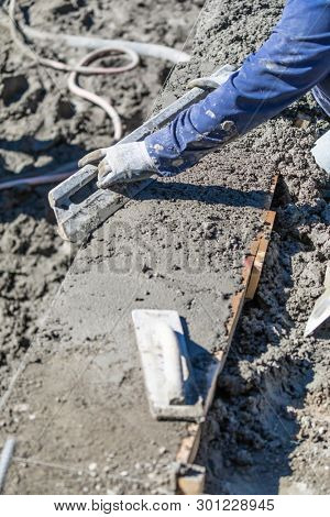 Pool Construction Worker Working With A Smoother Rod On Wet Concrete