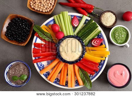Colorful Fresh Vegetables Cut Into Strips On A Plate And Various Types Of Humus.