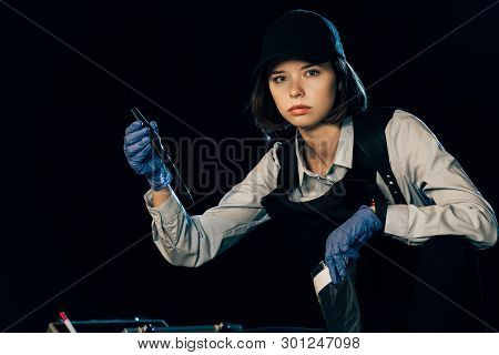 Investigator In Uniform Holding Knife And Ziploc Bag At Crime Scene