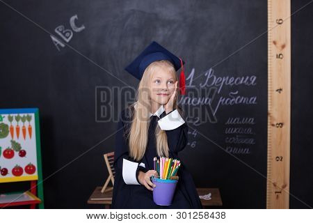 Back To School! Cheerful Girl At School With Pencils Near The Blackboard. School Concept. On The Bla