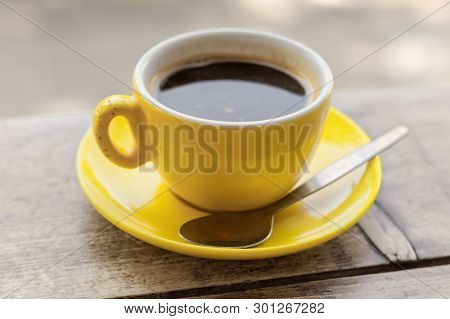 Chipped Yellow Coffee Cup And Saucer On A Wooden Table, Closeup With A Shallow Depth Of Field