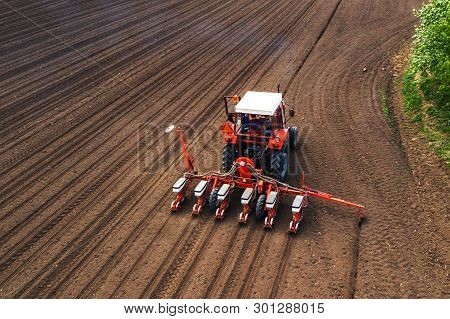 Aerial View Of Tractor With Mounted Seeder Performing Direct Seeding Of Crops On Plowed Agricultural
