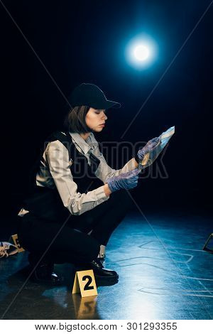Investigator In Rubber Gloves Holding Ziploc Bag With Dollar Banknote At Crime Scene